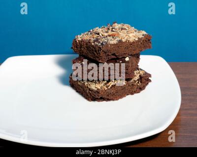 BROWNIES IN EINEM WEISSEN TELLER, GARNIERT MIT GERÖSTETEN MANDELN Stockfoto