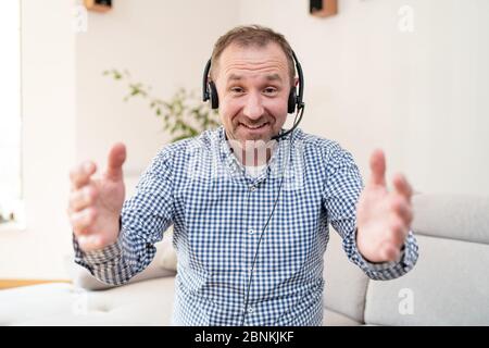 Telefonanbieter. Kundendienstmitarbeiter mit Headset im Call Center zu Hause. Home Office. Lächelnder Mann mit Ohrhörern auf dem Kopf. Stockfoto