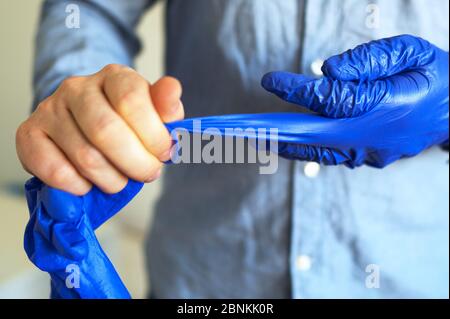 Der Mann zieht seine medizinischen Handschuhe aus. Covid-19 Prävention. Stockfoto