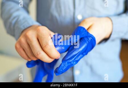 Der Mann zieht seine medizinischen Handschuhe aus. Covid-19 Prävention. Stockfoto