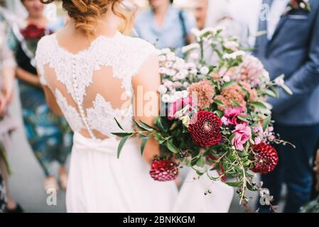 Brautstrauß aus nächster Nähe, das Bouquet besteht aus roten und weißen Rosen und Eukalyptus. Die Braut hält den Strauß Stockfoto