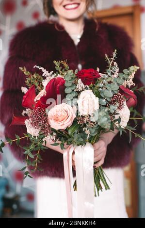 Brautstrauß aus nächster Nähe, das Bouquet besteht aus roten und weißen Rosen und Eukalyptus. Die Braut hält den Strauß Stockfoto