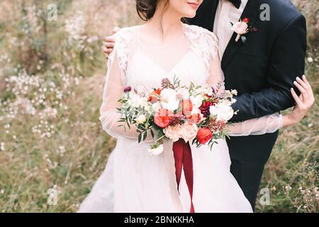 Brautstrauß aus nächster Nähe, das Bouquet besteht aus roten und weißen Rosen und Eukalyptus. Die Braut hält den Strauß Stockfoto