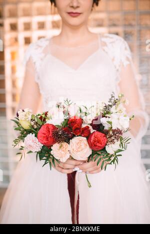 Brautstrauß aus nächster Nähe, das Bouquet besteht aus roten und weißen Rosen und Eukalyptus. Die Braut hält den Strauß Stockfoto