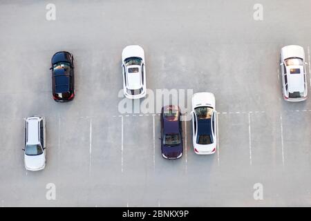 Draufsicht auf einen asphaltierten Parkplatz mit leeren Plätzen und stehenden Autos in schwarz-weiß in der Nähe eines Wohnhauses oder Supermarkt. Stockfoto