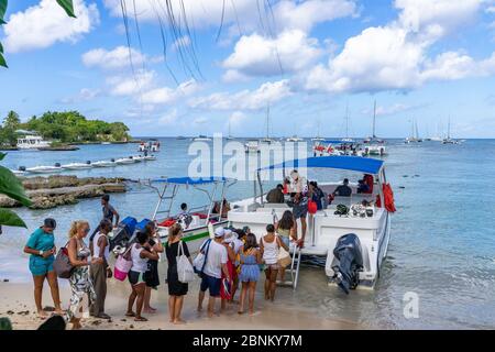 Amerika, Karibik, große Antillen, Dominikanische Republik, La Altagracia Provinz, Bayahibe, Touristen steigen an Bord eines Ausflugsboots am Strand von Bayahibe Stockfoto