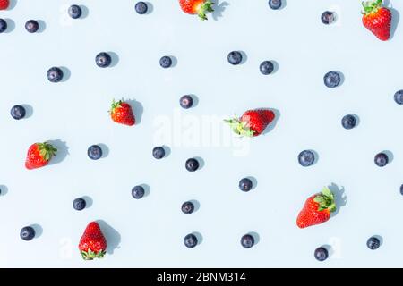 Buntes Fruchtmuster aus Heidelbeeren und Erdbeeren auf blauem Hintergrund. Draufsicht flach gelegt. Stockfoto