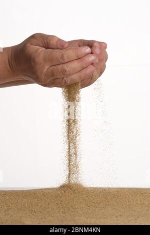 Bewegung einfrieren. Die Hände der Männer werden in einer Handvoll gelbem Sand gehalten, der von unten auf einen Haufen fällt. Stockfoto