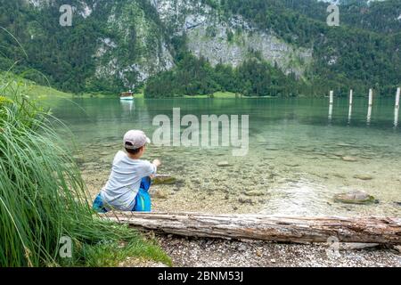 Europa, Deutschland, Bayern, Bayerische Alpen, Berchtesgaden, Königssee, Junge lässt Steine am Königssee bei Berchtesgaden springen Stockfoto