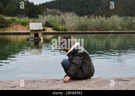 Dark Boy beobachten das Wasser Floß mit Enten, Farben der Natur Stockfoto