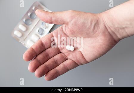 Nahaufnahme der Außenhandfläche mit einem Tablet. Mann mit einer weißen Pille in der Hand, Konzeptbild. Stockfoto