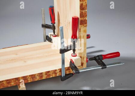 Bau eines Holzregals, Do-it-yourself-Produktion, Schritt für Schritt, Schritt 8 Stabilisierung der Frischklebung mit Hilfe von Schraubklemmen und einer Hilfsschiene, die nach dem Aushärten entfernt wird. Stockfoto