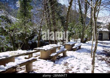 Erholungsgebiet in schneebedeckten Berg im Winter. Tische und Stühle voller Schnee umgeben von Bäumen Stockfoto