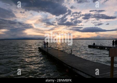 Landschaft eines Sees mit Sturmwolken, bewegende Gewässer Schilf im Wasser, bläuliche Töne, Pier, Stockfoto