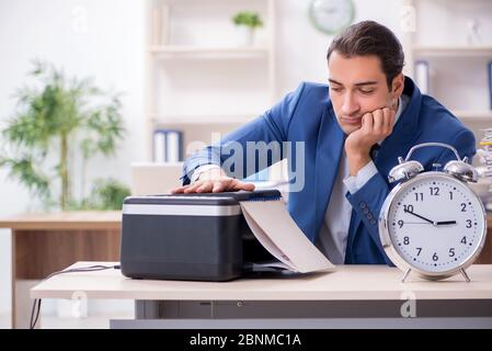 Junge Mitarbeiter von Kopien beim Kopieren von Maschine Stockfoto
