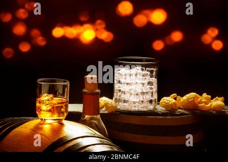 Whiskyglas mit Eiswürfeln und Chips auf Whiskyfässern Stockfoto