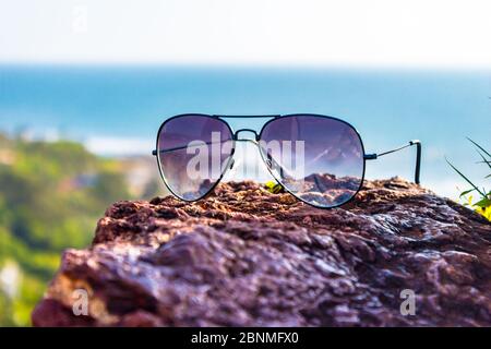 Aviator Sonnenbrille im Fokus mit Vagator Beach von North Goa, Goa, Indien im Hintergrund. Luftaufnahme des Vagator Strandes vom Gipfel des Chapora Fort Stockfoto