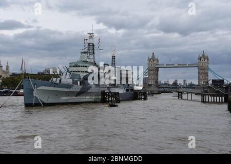 HMS Belfast ist ein historisches Kriegsschiff und Museum, das Geschichten vom Leben an Bord erforscht. Gelegen an der Themse, London, Großbritannien. Tower Bridge nach hinten Stockfoto