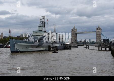 HMS Belfast ist ein historisches Kriegsschiff und Museum, das Geschichten vom Leben an Bord erforscht. Gelegen an der Themse, London, Großbritannien. Tower Bridge nach hinten Stockfoto