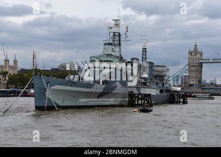 HMS Belfast ist ein historisches Kriegsschiff und Museum, das Geschichten vom Leben an Bord erforscht. Gelegen an der Themse, London, Großbritannien. Tower Bridge nach hinten Stockfoto