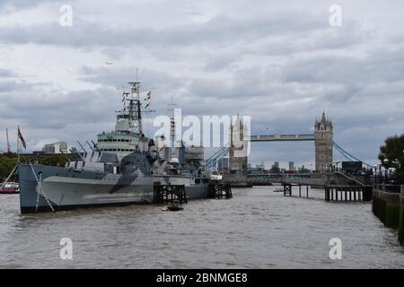 HMS Belfast ist ein historisches Kriegsschiff und Museum, das Geschichten vom Leben an Bord erforscht. Gelegen an der Themse, London, Großbritannien. Tower Bridge nach hinten Stockfoto