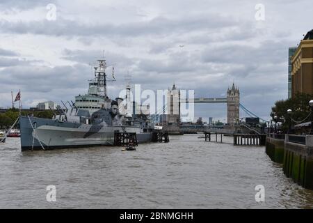 HMS Belfast ist ein historisches Kriegsschiff und Museum, das Geschichten vom Leben an Bord erforscht. Gelegen an der Themse, London, Großbritannien. Tower Bridge nach hinten Stockfoto