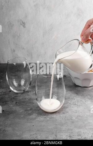 Kochen Sie einen beliebten koreanischen Dalgon Kaffee Schritt für Schritt. Gießen Sie Milch in Kaffeeglas auf grauem Hintergrund Stockfoto