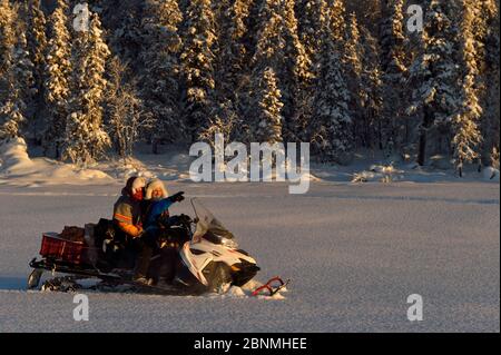 Nils-Torbjorn Nutti, Eigentümer und Betreiber bei Nutti Sami Siida, und Klara Enbom-Burreau auf einer Motorschlittenfahrt in die Wildnis, Jukkasjarvi, Lappland, Lappland, Lap Stockfoto