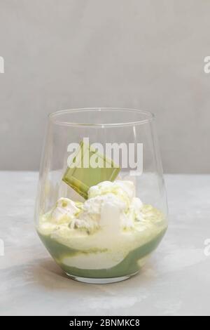 Matcha Affogato Dessert. Kugeln Vanilleeis mit Matcha-Tee in einer Glasschale auf neutralem Hintergrund Stockfoto