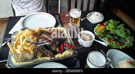 Teller mit Essen und Bier, Roastbeef, Chips, Reis, Salat Stockfoto