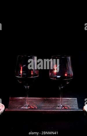 Zwei Weingläser auf einer Fliese, auf schwarzem Hintergrund und Utensilien für Wein gefüllt Stockfoto