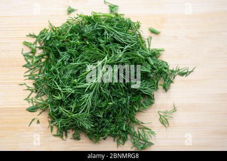 Nahaufnahme von oben von gehackten frischen grünen Dill, geschnitten Dill auf Holzbrett in der Küche Stockfoto