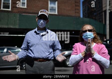 New York City, USA. Mai 2020. Zwei Personen, die wegen der COVID-19-Pandemie Gesichtsmasken tragen, beten außerhalb der römisch-katholischen Kirche der Saint Bartholomew-Gemeinde während Gottesdiensten, die über einen Lautsprecher stattfinden, während die Menschen Nahrungsmittelhilfe erhalten, im Elmhurst-Viertel des New Yorker Stadtbezirks Queens, NY, 15. Mai 2020. Katholische Wohltätigkeitsorganisationen Brooklyn und Queens bieten kostenlose Nahrung in der Kirche aufgrund der zunehmenden Nahrungsmittelunsicherheiten aufgrund der Auswirkungen von COVID-19 auf die Wirtschaft, wo 1600 Essenskarten an Menschen in der Schlange so früh wie 3 Uhr morgens gegeben wurden, jede Person erhielt Taschen mit genügend Nahrung für Stockfoto