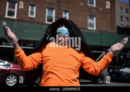 New York City, USA. Mai 2020. Ein Mann, der wegen der COVID-19-Pandemie eine Gesichtsmaske trägt, betet außerhalb der römisch-katholischen Kirche der Saint Bartholomew Parish während Gottesdiensten, die über einen Lautsprecher stattfinden, während die Menschen Nahrungsmittelhilfe erhalten, im Elmhurst-Viertel des New Yorker Stadtbezirks Queens, NY, 15. Mai 2020. Katholische Wohltätigkeitsorganisationen Brooklyn und Queens bieten kostenlose Nahrung in der Kirche aufgrund der zunehmenden Nahrungsmittelunsicherheiten aufgrund der Auswirkungen von COVID-19 auf die Wirtschaft, wo 1600 Essenskarten an Menschen in der Schlange so früh wie 3 Uhr morgens gegeben wurden, jede Person erhielt Taschen mit genügend Nahrung, um eine zu machen Stockfoto