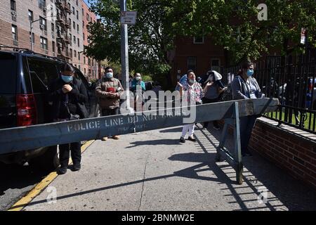 New York City, USA. Mai 2020. Die Menschen tragen Gesichtsmasken aufgrund der COVID-19-Pandemie und beten auf dem Bürgersteig vor der römisch-katholischen Kirche der Saint Bartholomew Parish während Gottesdiensten, die über einen Lautsprecher stattfinden, während die Menschen Nahrungsmittelhilfe erhalten, im Elmhurst-Viertel des New Yorker Stadtbezirks Queens, NY, 15. Mai 2020. Stockfoto