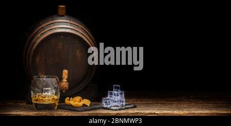 Whiskyglas mit Eiswürfeln und Chips vor einem Whiskyfass Stockfoto