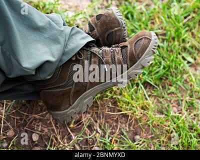 Füße eines Mannes in Wildlederschuhen sitzen im Garten Stockfoto