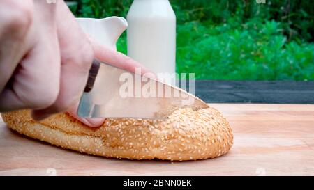 Mann, der Brot auf Holzbrett hackt. Stockfoto