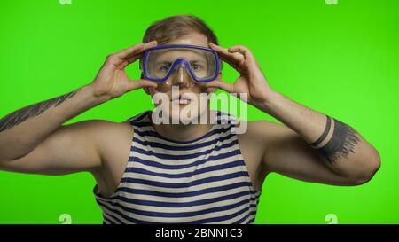 Emotional gut aussehend Kerl Tourist in Unterwasser Schwimmbrille Maske tragen gestreiften Seemann Hemd Weste. Chroma-Taste Hintergrund. Muskulöser Seemann Mann. Konzept des Tourismus, Meer Resorts Stockfoto
