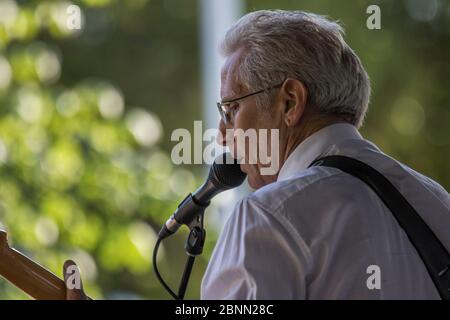 Scharf gekleideter Musiker, spielt einen Fender Statocaster, singt und im Outdoor-Konzert. Stockfoto