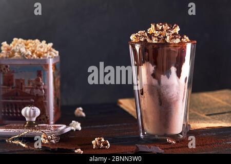 Milchshake mit Schokolade und Popcorn vor dunklem Hintergrund. Stockfoto