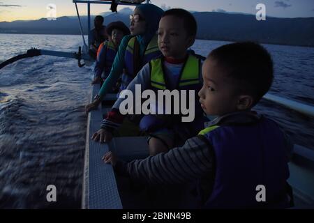 Einige Touristen gehen mit einem Boot in der Nähe von Lovina Beach Bali in der Morgendämmerung aufs Meer. Stockfoto