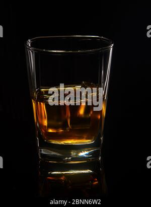 Glas Whiskey mit Eis auf schwarzem Hintergrund mit Spiegelung. Stockfoto