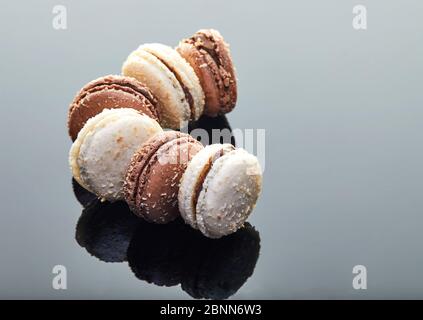 Makronen mit Kokosnussgeschmack auf grauem Hintergrund mit Spiegelung. Stockfoto