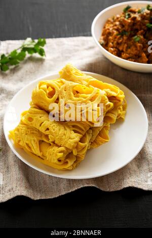 Hausgemachte Net Crepe Roti Jala auf einem weißen Teller auf schwarzem Hintergrund, Low-Winkel-Ansicht. Stockfoto