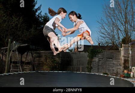 Zwei junge Mädchen springen auf Trampolin in Woking - England Stockfoto