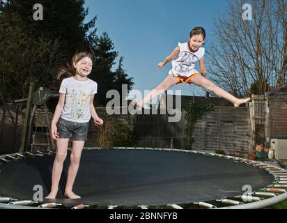 Zwei junge Mädchen springen auf Trampolin in Woking - England Stockfoto