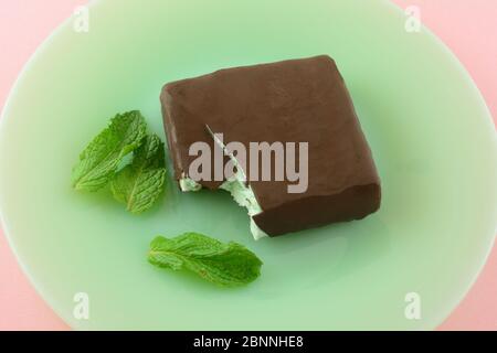 Minze Chocolate Chip Eisbar mit Milchschokolade auf grünem Teller mit frischen Minzblättern auf rosa Hintergrund bedeckt Stockfoto