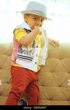 Porträt eines süßen südasiatischen Jungen trägt ein Hemd und Fedora-Hut. Essen seine Hand Stockfoto