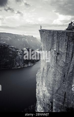 Person auf der Klippe von Preikestolen blickt über den Lysefjord, Rogaland, Norwegen Stockfoto